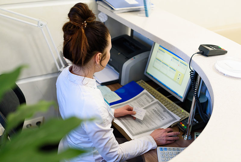 A woman sitting at a desk in an office, working on a computer.