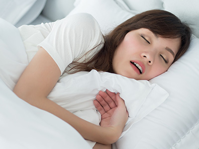 A woman lying in bed, appearing to be asleep with her mouth open.